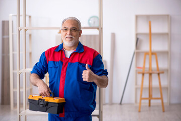 Old male carpenter working indoors