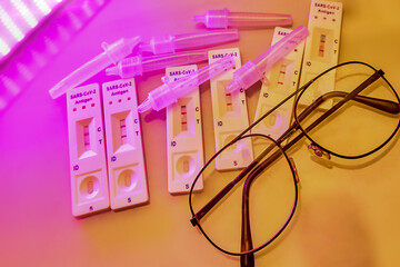 6 covid-19 antigen self-tests positive, buffer bottles and thin black-rimmed glasses on a light...