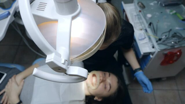 A woman dentist works with a patient in the dentist's office, top view. A patient with a cheek retractor in his mouth in a modern dental clinic