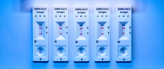5 covid-19 antigen self-tests positive on white background. Medical concept - Mutated coronavirus...