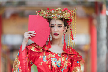 Asian girl wearing red traditional Chinese Vintage decoration holding red envelopes in hand and lanterns with the Chinese text Blessings written on it Is a Fortune blessing for Chinese New Year.