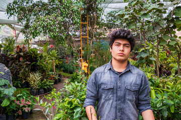 Young male garden owner, growing plants in greenhouse, small business entrepreneur concept