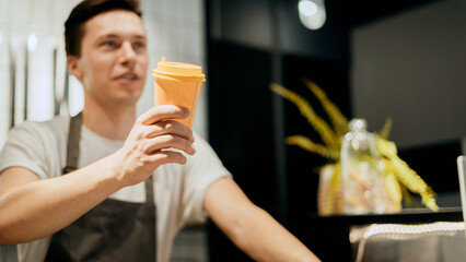 Male barista waiter employee in uniform in a cafe selling takeaway coffee