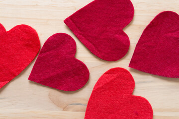 several red felt hearts on wooden background