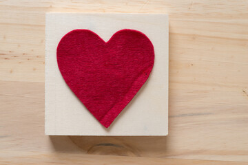 isolated felt heart on the back of a wooden box, sitting on a wooden surface