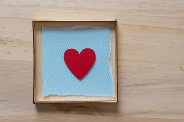 red heart isolated in a box with blue paper and wood
