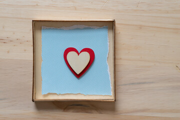 isolated hearts on blue and inside a box on a wooden surface
