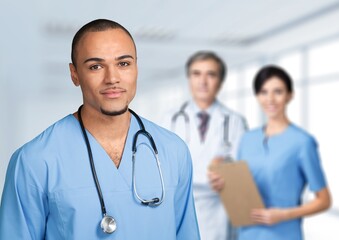 Portrait of happy young nurse in uniform with healthcare team in background. Successful doctor and nurses