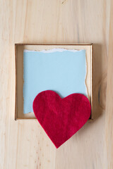 shallow box, blue paper with pattern, felt heart, and wooden surface