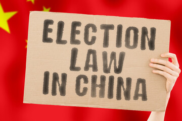 The phrase " Election law in China " on a banner in men's hand with blurred Chinese flag on the background. Constitution. Political. Senate. Beijing. Electorate. Majority