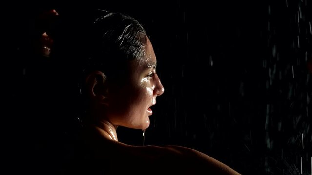 passionate and sensual wet women is dancing in rain or in shower in darkness