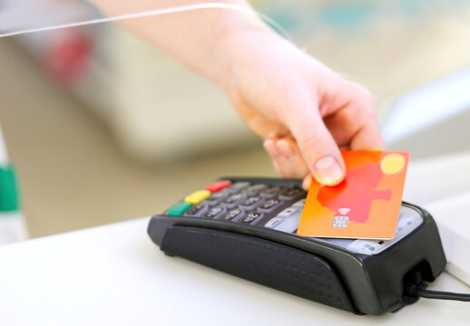 customer pay hold credit card with contactless nfc technology concept. transaction in pharmacy store on wireless terminal pos reader machine. close up