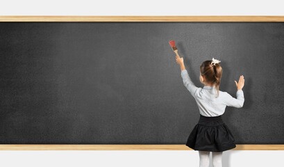 Student child writes with chalk on a blackboard solution of an example in mathematics.