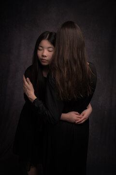 painterly dark studio portrait of mom and daughter in loving embrace in rembrandt style