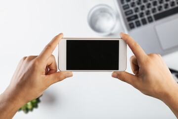 Hands hold smartphone with blank screen
