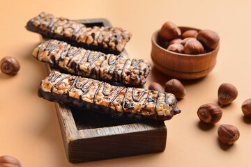 Board with tasty chocolate nut bars on color background
