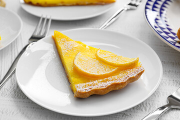 Plate with slice of tasty lemon tart on table