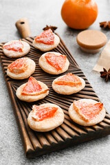 Board with tasty grapefruit cookies on table