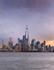 Obraz premium Freedom Tower, Manhattan downtown skyline and Hudson River views from Hoboken, New Jersey, sunset on a stormy afternoon. 