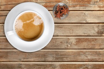 Cup of pumpkin spice late with cinnamon sticks, in a rustic moody and vintage atmosphere