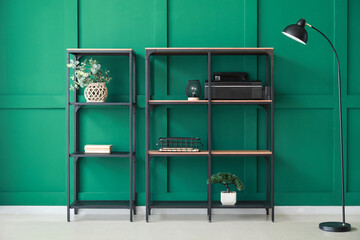 Shelves with modern decor and floor lamp near green wall in room