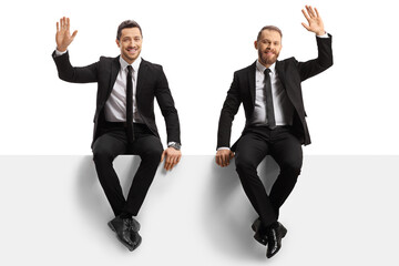 Two young businessmen sitting on a panel and waving