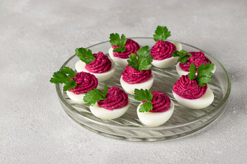 Eggs stuffed with beets and cream cheese, garnished with parsley on a gray background