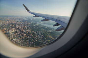 View from airplane window on the wing. Airplane going for landing. Plane Window as Descending Over Metropolitan Urban City Landscape.