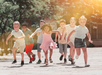 Fototapeta na wymiar Happy children running in race and laughing outdoors at sunny day