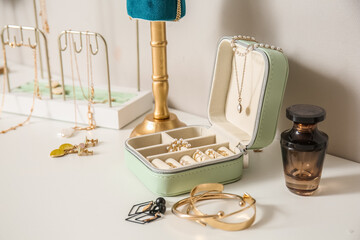 Box with different stylish jewelry on white table near light wall