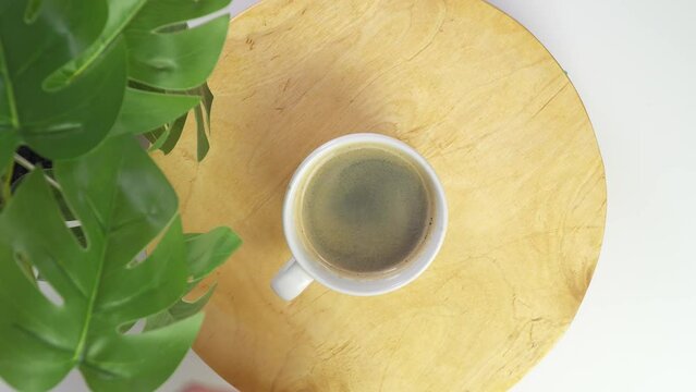 Top view of hot coffee cup on table. flat lay on white desktop. Place text. Espresso Hot aromatic drink. Coffees and health. A woman hand takes cup. Wooden circle and green cozy in caffe. return put.