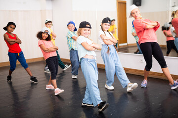 Cheerful preteen girls and boys hip hop dancers doing dance workout with female trainer during...