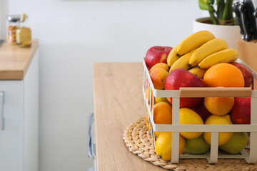 Basket with tasty fruits on table in kitchen, closeup