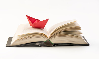  Origami red paper boat on a book. Close up Macro photography. Concept of traveling and 

research - knowledge
