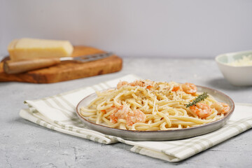 Flat plate with pasta spaghetti with heavy cream and roasted shrimps with garlic sauce and parmesan cheese on concrete surface