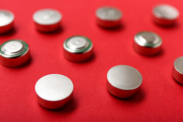 Metal lithium button cell batteries on red background, closeup