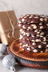 Wooden board of tasty cookies with white chocolate chips and Christmas balls on table