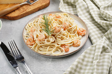 Flat plate with pasta spaghetti with heavy cream and roasted shrimps with garlic sauce and parmesan cheese on grey concrete surface