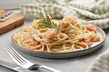 Flat plate with pasta spaghetti with heavy cream and roasted shrimps with garlic sauce and parmesan cheese on grey concrete surface