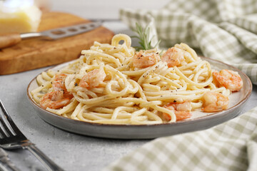 Deep grey japanese style bowl with pasta spaghetti with heavy cream and roasted shrimps with garlic sauce and parmesan cheese, black chopsticks on grey concrete surface