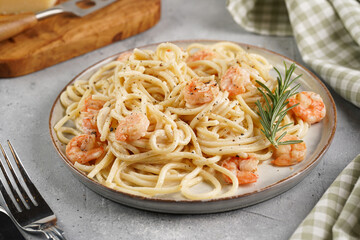 Deep grey japanese style bowl with pasta spaghetti with heavy cream and roasted shrimps with garlic sauce and parmesan cheese, black chopsticks on grey concrete surface