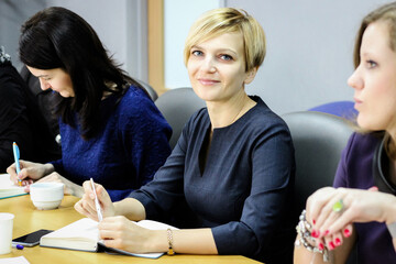Business woman in a meeting sitting at the table holding a pen in her hands and smiling