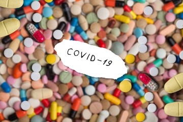 A set of colored pillls and covid-19 text