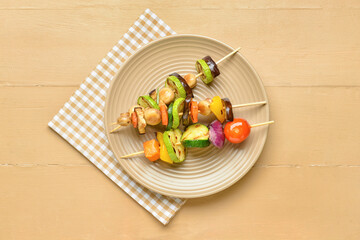 Plate with tasty vegetable skewers on wooden background