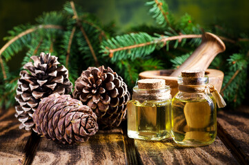 Natural aromatic and healing oil of pine nuts in glass bottles pine cones on a wooden table,...