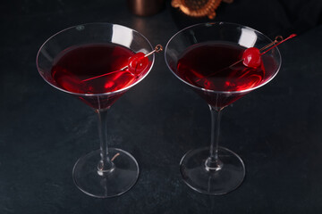 Glasses of tasty Manhattan cocktail on black background