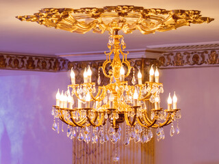 Luxurious retro chandelier with golden swirls and electric light bulbs which looks like candles....