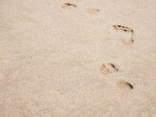 Male footprints on a sandy beach. A chain of bare footprints. Trail to follow. Outline of feet tracks.