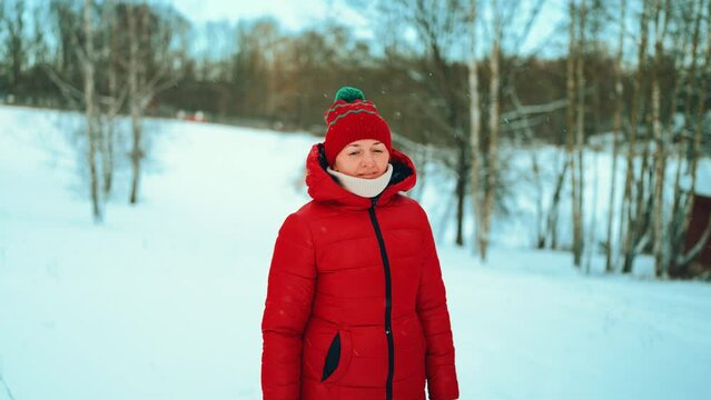 a girl in a red jacket stands on a frozen lake on a background of a snowy forest winter cold.