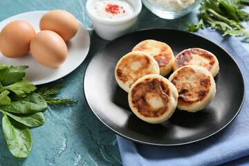 Plate with tasty cottage cheese pancakes, sauce and eggs on color background, closeup